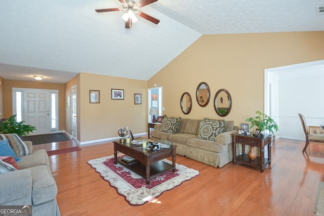 living room with ceiling fan, light hardwood / wood-style floors, and vaulted ceiling