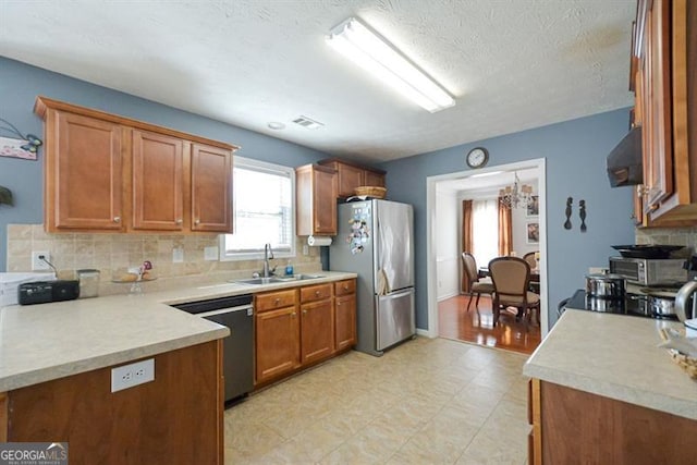 kitchen featuring a textured ceiling, ventilation hood, stainless steel appliances, sink, and a notable chandelier