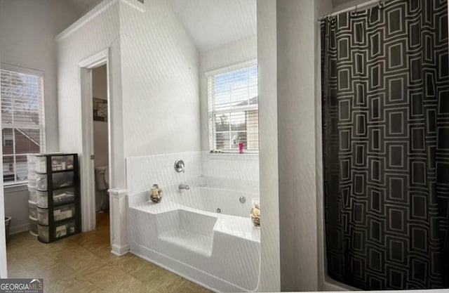 bathroom with tile patterned flooring, a tub to relax in, toilet, and lofted ceiling