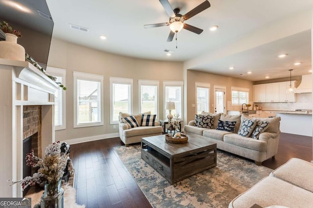 living room featuring dark hardwood / wood-style floors, ceiling fan, and a fireplace