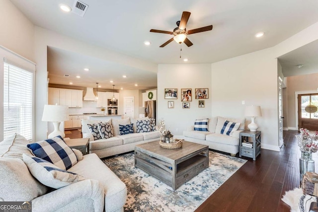 living room featuring a healthy amount of sunlight, ceiling fan, and dark wood-type flooring