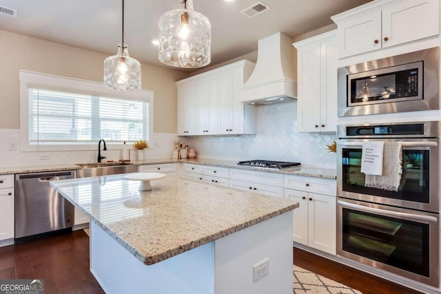 kitchen with white cabinets, a kitchen island, premium range hood, and stainless steel appliances