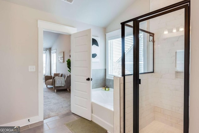 bathroom with tile patterned floors, shower with separate bathtub, and vaulted ceiling