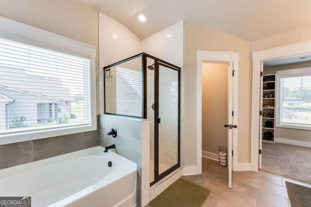 bathroom with tile patterned flooring, separate shower and tub, vaulted ceiling, and a wealth of natural light