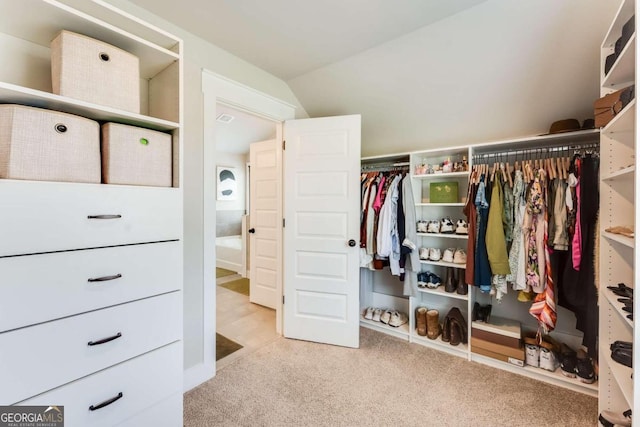 spacious closet featuring light colored carpet and vaulted ceiling