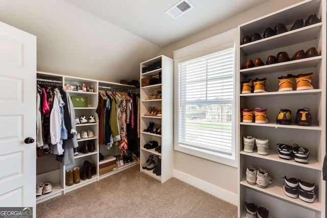 walk in closet with carpet floors and lofted ceiling