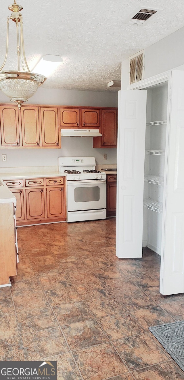 kitchen featuring under cabinet range hood, white range with gas cooktop, visible vents, and light countertops