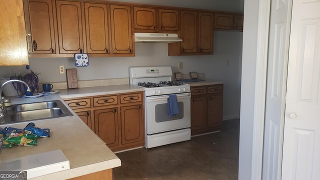 kitchen featuring under cabinet range hood, white range with gas stovetop, a sink, light countertops, and brown cabinets