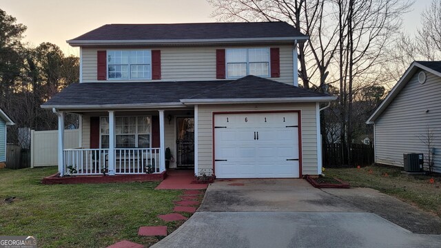 view of front property featuring a porch, a garage, a yard, and central AC