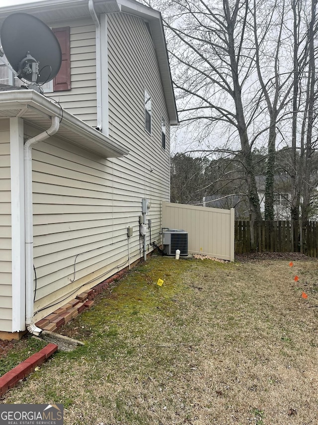 view of home's exterior with a yard, cooling unit, and fence