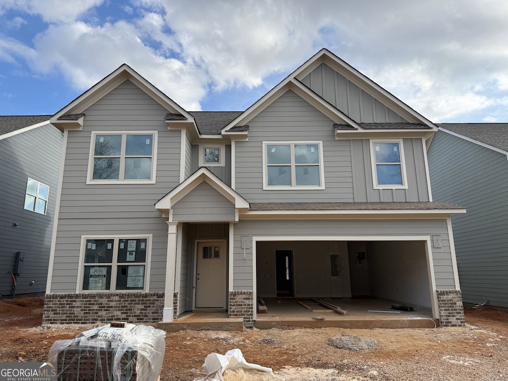 craftsman-style home featuring an attached garage, brick siding, board and batten siding, and roof with shingles