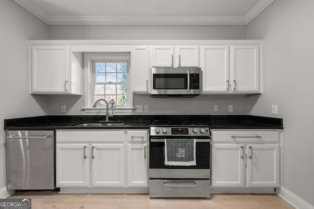 kitchen featuring dark stone counters, white cabinets, crown molding, sink, and appliances with stainless steel finishes