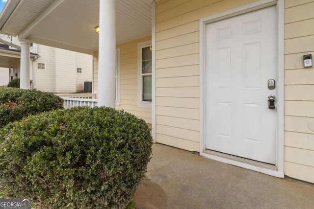 view of exterior entry featuring cooling unit and covered porch