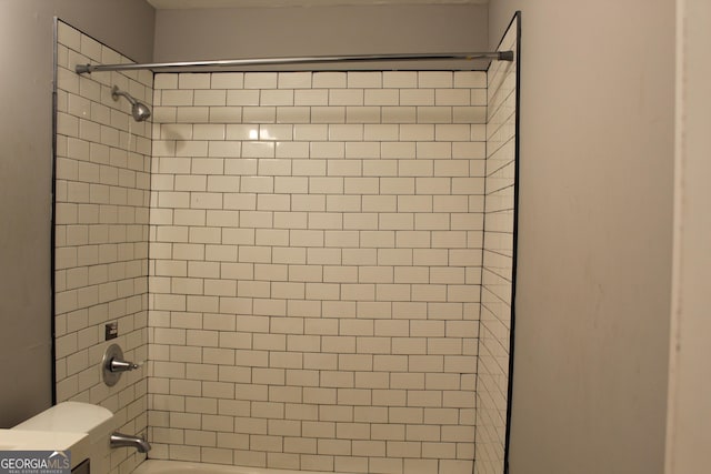 details featuring tiled shower / bath combo and toilet