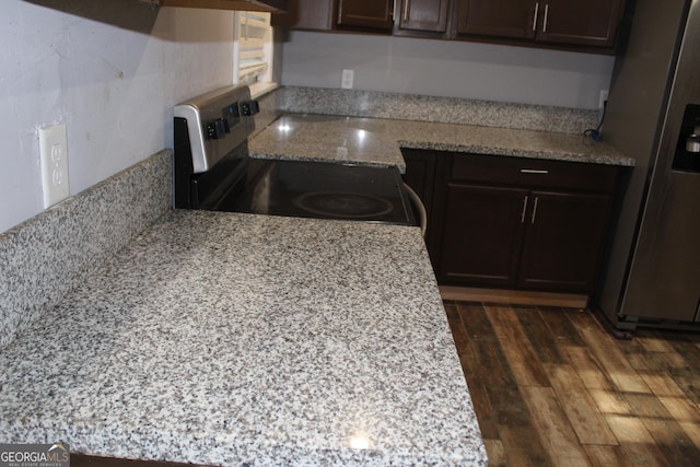 kitchen with dark brown cabinets, dark hardwood / wood-style flooring, light stone countertops, and appliances with stainless steel finishes