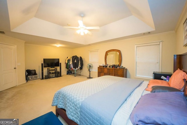 carpeted bedroom featuring a tray ceiling, ceiling fan, and ornamental molding