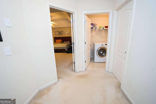 hall with washer / clothes dryer and light colored carpet