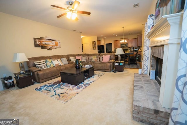 carpeted living room with a fireplace and ceiling fan with notable chandelier