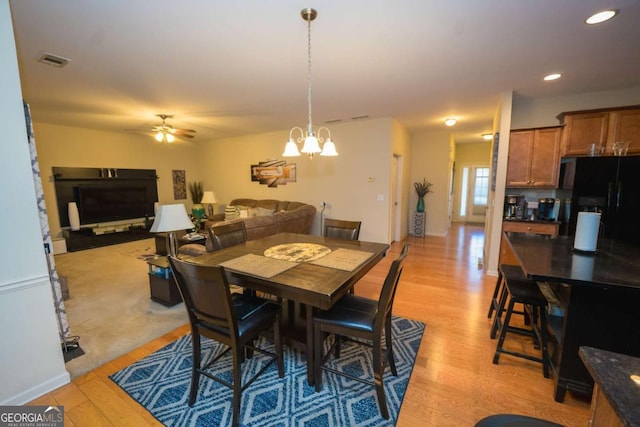 dining area with ceiling fan with notable chandelier and light wood-type flooring