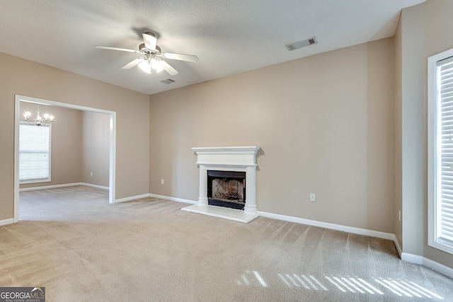 unfurnished living room with ceiling fan with notable chandelier and light colored carpet