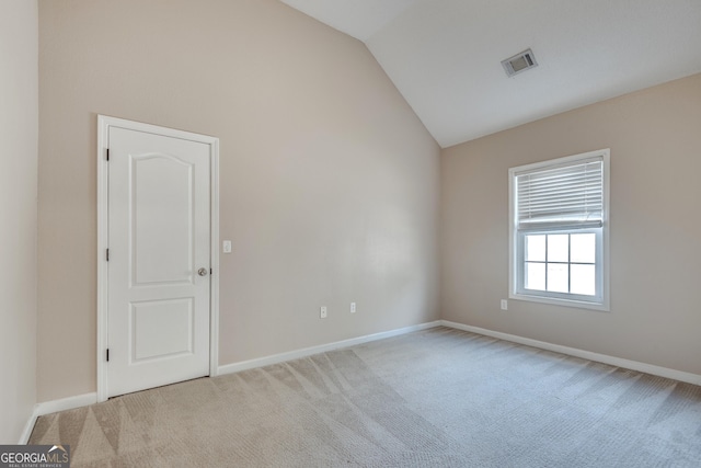 unfurnished room featuring light colored carpet and vaulted ceiling