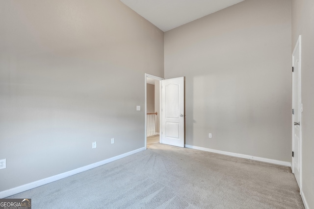 spare room with light carpet and high vaulted ceiling