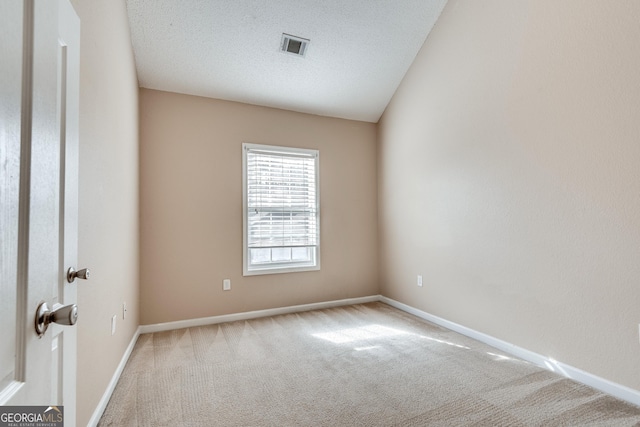 unfurnished room with lofted ceiling, carpet, and a textured ceiling