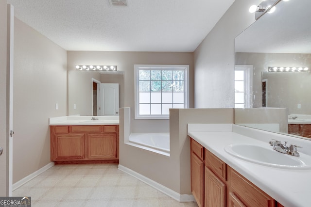 bathroom featuring a bathtub, vanity, and a textured ceiling