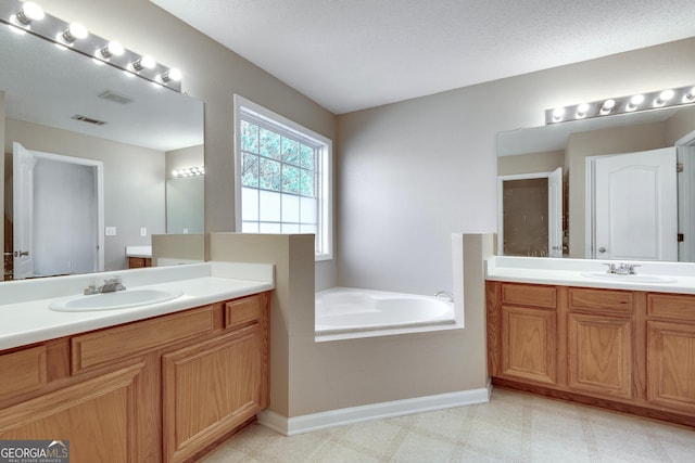 bathroom featuring a tub to relax in, vanity, and a textured ceiling