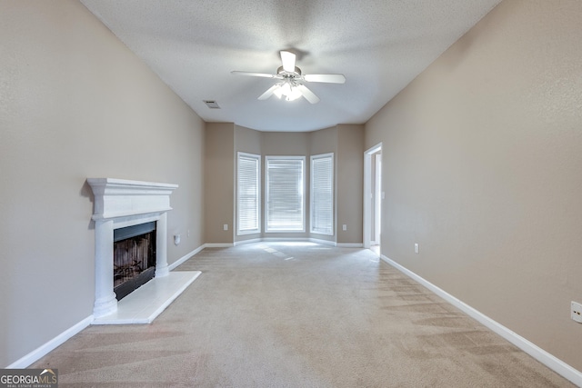 unfurnished living room with a textured ceiling, light colored carpet, and ceiling fan