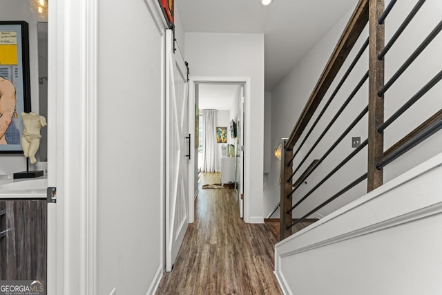 corridor with stairs, dark wood-style flooring, baseboards, and a barn door