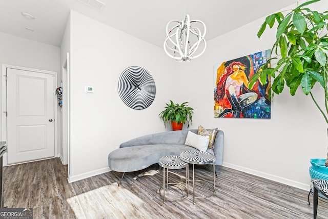 living area featuring a chandelier, wood finished floors, visible vents, and baseboards