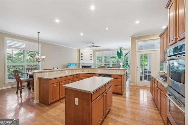 kitchen featuring pendant lighting, a center island, ceiling fan with notable chandelier, crown molding, and appliances with stainless steel finishes