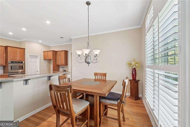 dining area with a notable chandelier, ornamental molding, and light hardwood / wood-style flooring