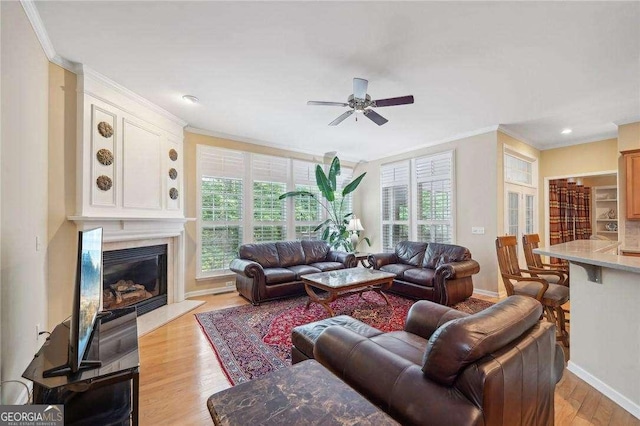 living room featuring ceiling fan, light wood-type flooring, and ornamental molding