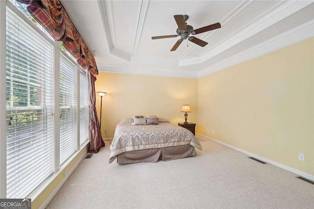 carpeted bedroom featuring multiple windows, a tray ceiling, ceiling fan, and ornamental molding