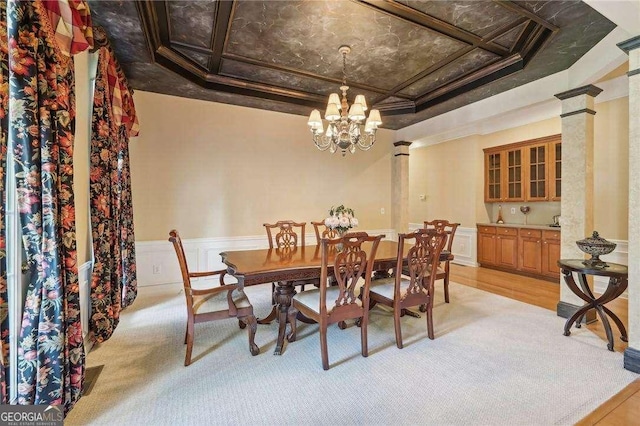 carpeted dining area with a chandelier, ornamental molding, ornate columns, and coffered ceiling