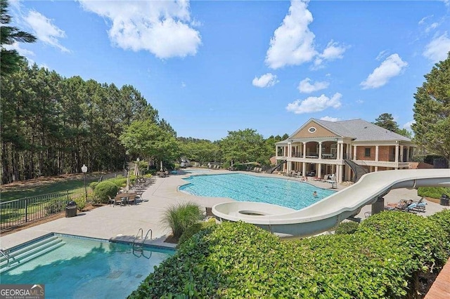 view of pool with a water slide and a patio