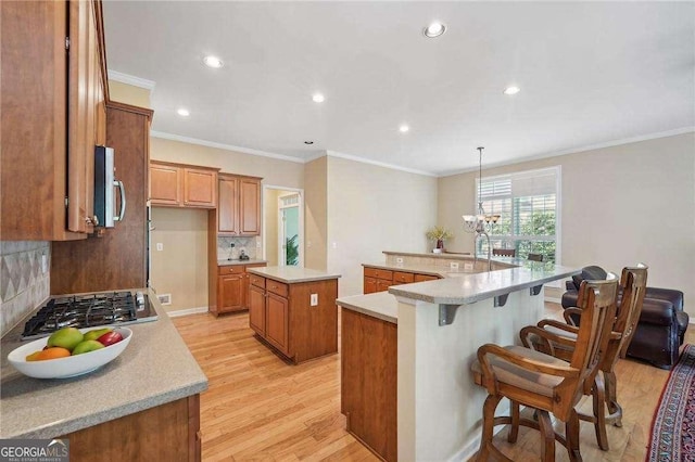 kitchen featuring decorative light fixtures, stainless steel appliances, a center island with sink, and tasteful backsplash