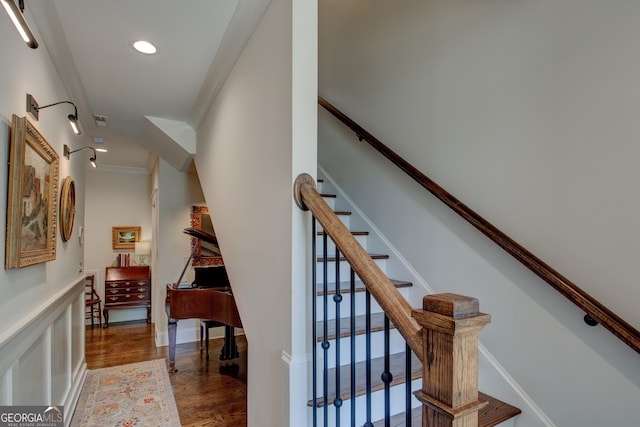 staircase with crown molding and wood-type flooring