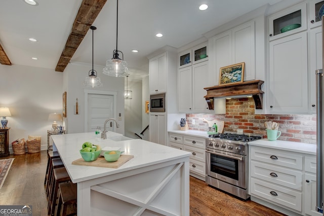 kitchen with a breakfast bar, sink, appliances with stainless steel finishes, beam ceiling, and white cabinetry