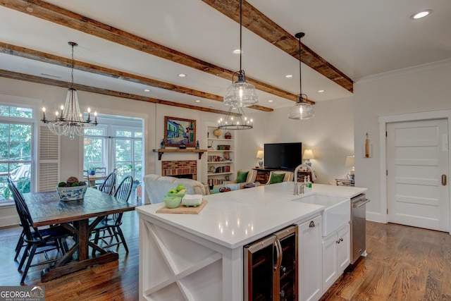 kitchen with wine cooler, a kitchen island with sink, a fireplace, and decorative light fixtures