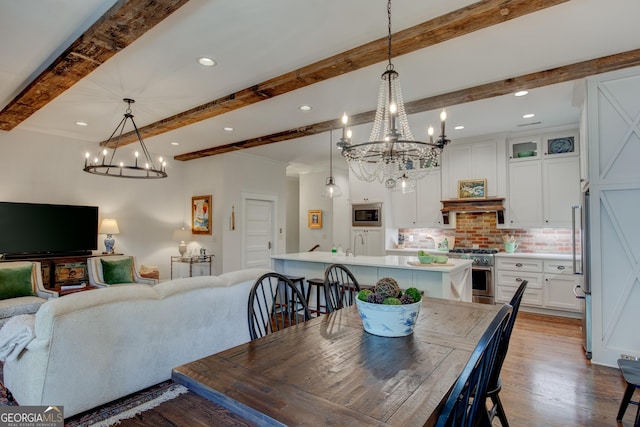 dining area with beam ceiling, light wood-type flooring, and sink