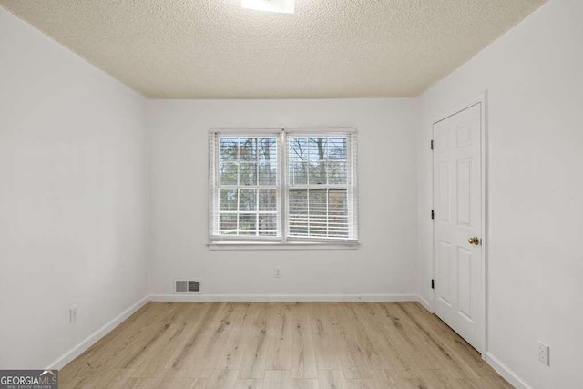 unfurnished room featuring light hardwood / wood-style flooring and a textured ceiling