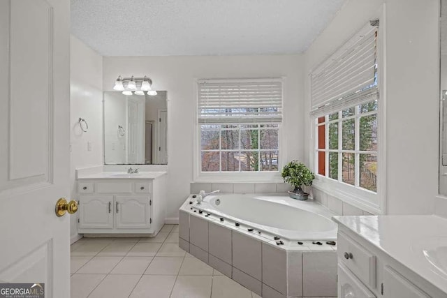 bathroom with vanity, a textured ceiling, tiled bath, and tile patterned floors