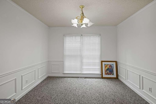 carpeted spare room featuring a textured ceiling, an inviting chandelier, and ornamental molding