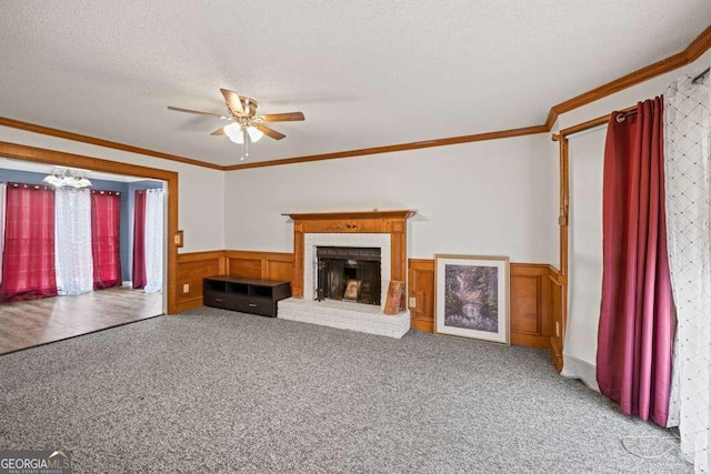 unfurnished living room with a textured ceiling, ceiling fan, crown molding, a fireplace, and carpet floors