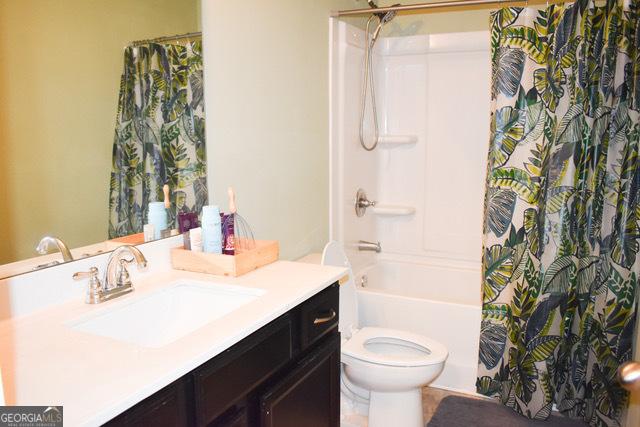 full bathroom featuring shower / tub combo with curtain, vanity, and toilet