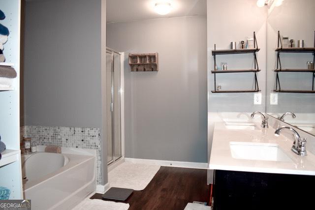 bathroom with wood-type flooring, vanity, and independent shower and bath