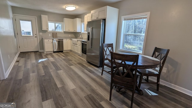 kitchen with dark wood-type flooring, stainless steel appliances, sink, and white cabinets